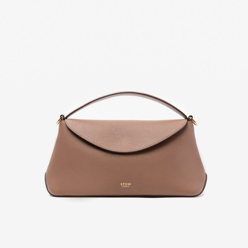 STOW London's East West in Mocha pebbled leather featuring gold-coated stainless steel hardware on a light grey background