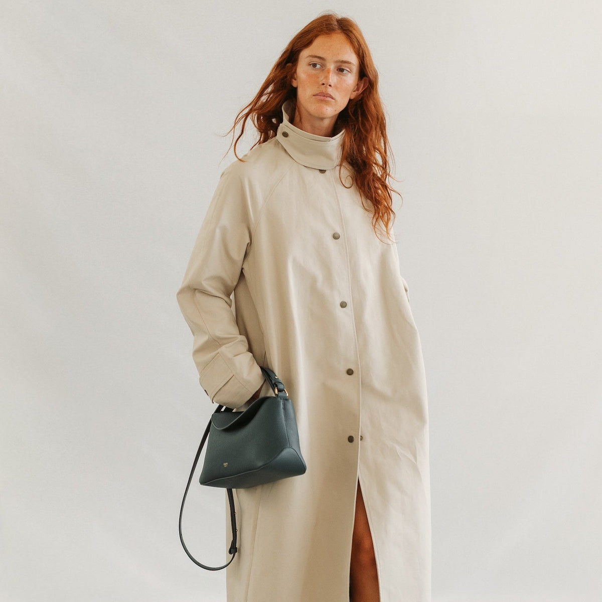 Model in a beige coat styling STOW London's East West in New Forest pebbled leather featuring gold-coated stainless steel hardware 