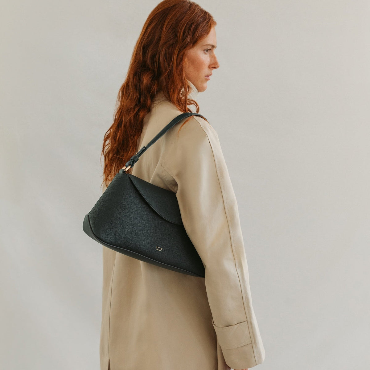 Model wearing STOW London's East West in New Forest pebbled leather featuring the detachable shoulder strap and gold-coated stainless steel hardware 