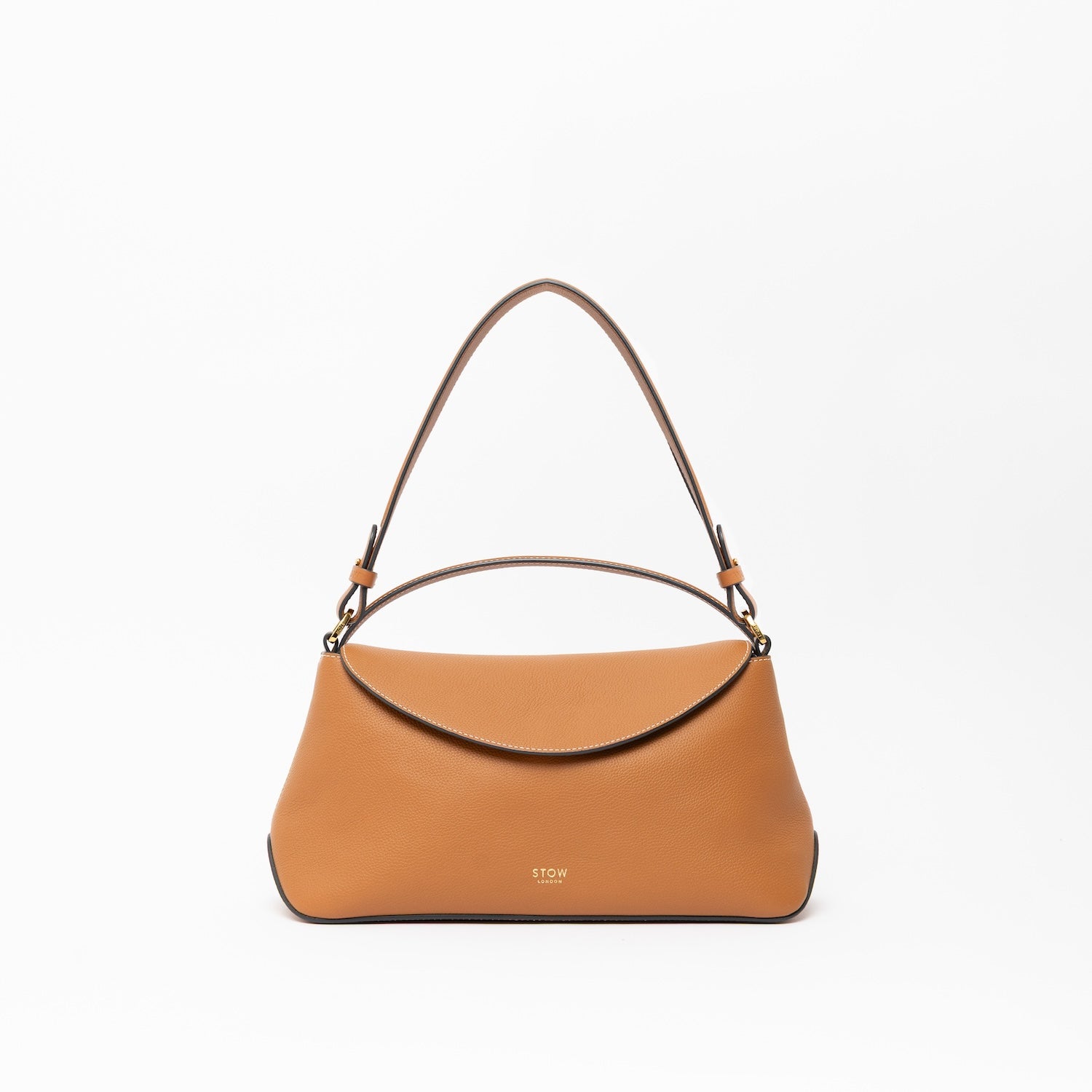 STOW London's East West, detachable shoulder strap and top handle in Earth Tan leather on a light grey background featuring gold hardware and details 
