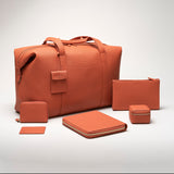 Family of STOW products all in the Clay Orange colour including Leather Weekend Bag, First Class Folio and Leather Cardholder.
