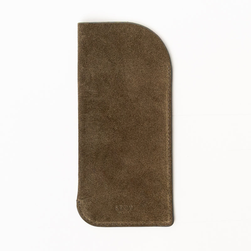 STOW London's Glasses Case in Dark Green suede leather on a light grey background featuring an embossed STOW London on front 