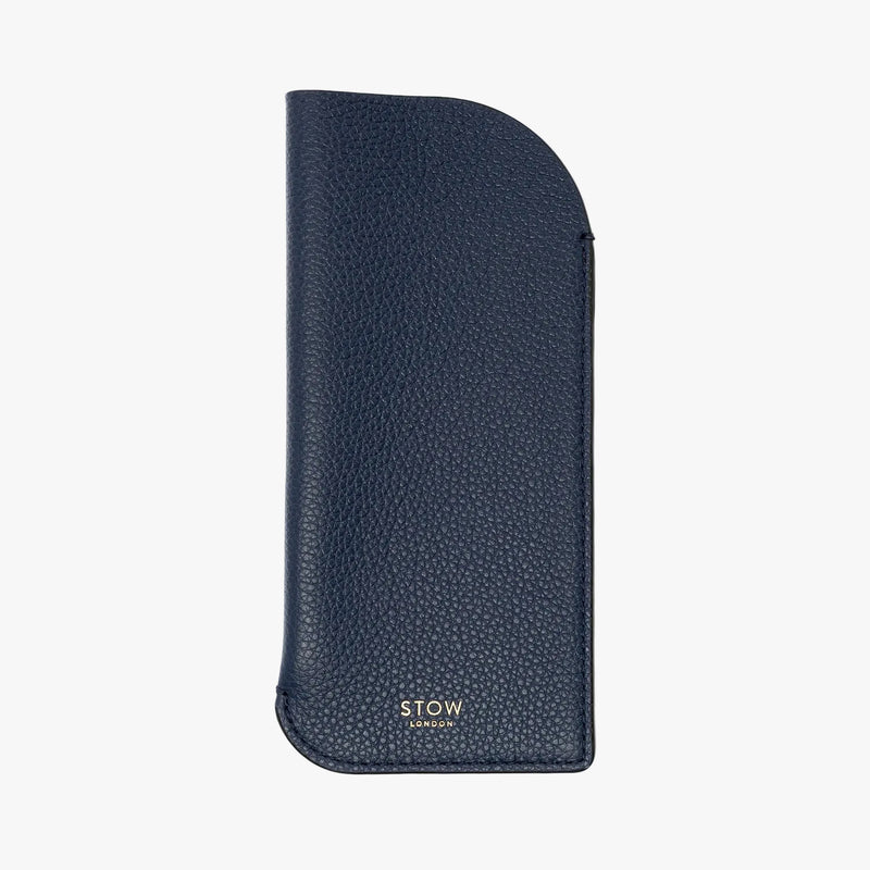 STOW London's Glasses Case in Navy pebbled leather on a light grey background featuring a small gold embossed logo on the front bottom