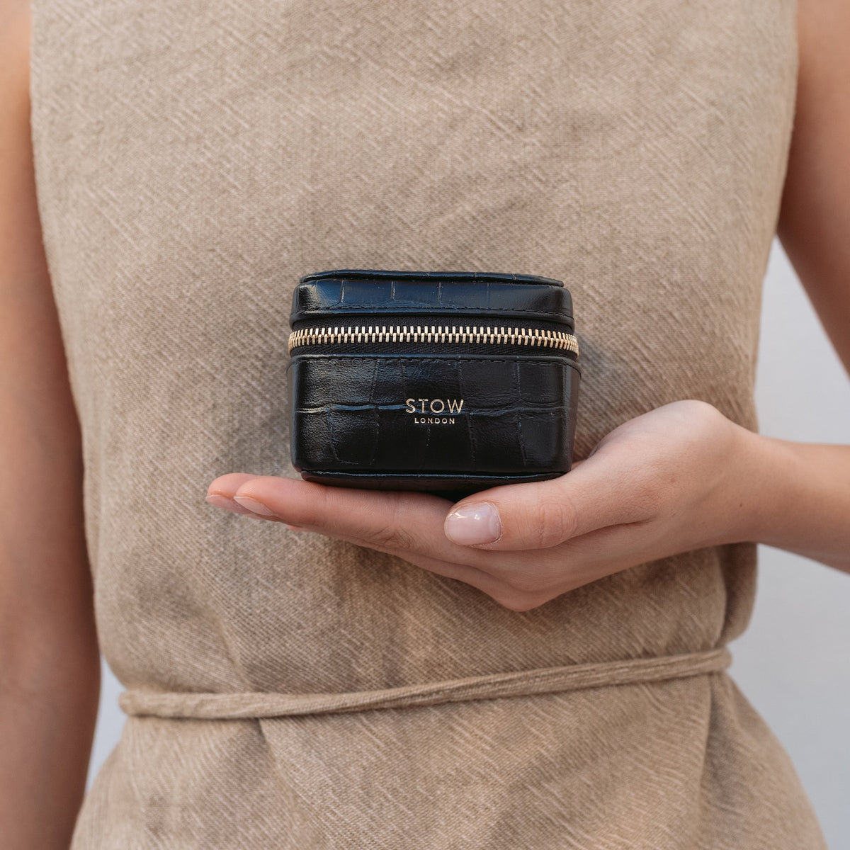 Model holding STOW London's Hester Jewellery Case in Black embossed croc leather featuring a small gold embossed logo on the front 