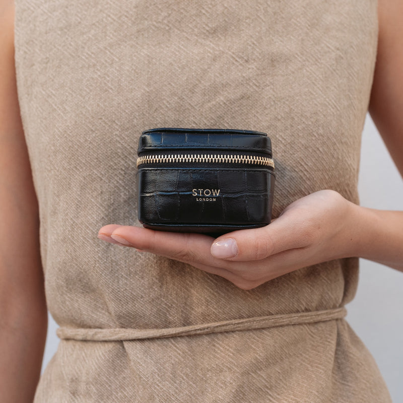 Model holding STOW London's Hester Jewellery Case in Black embossed croc leather featuring a small gold embossed logo on the front 