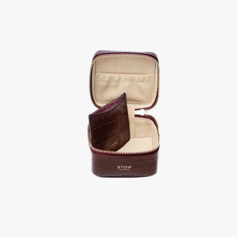 STOW London's Hester Jewellery Case in Burgundy Embossed Croc leather on a light grey background with zipper open showing the light Goat's suede interior, the elasticated pocket and leather slip pouch