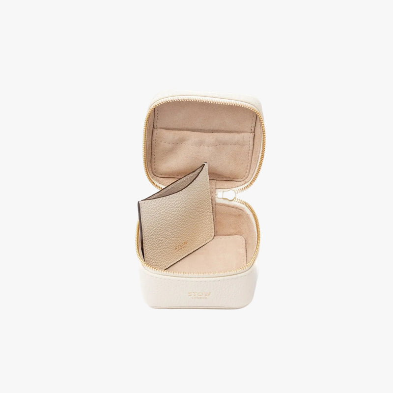 STOW London's Hester Jewellery Case in Spring Moon pebbled leather on a light grey background with zipper open showing the light Goat's suede interior, the elasticated pocket and leather slip pouch