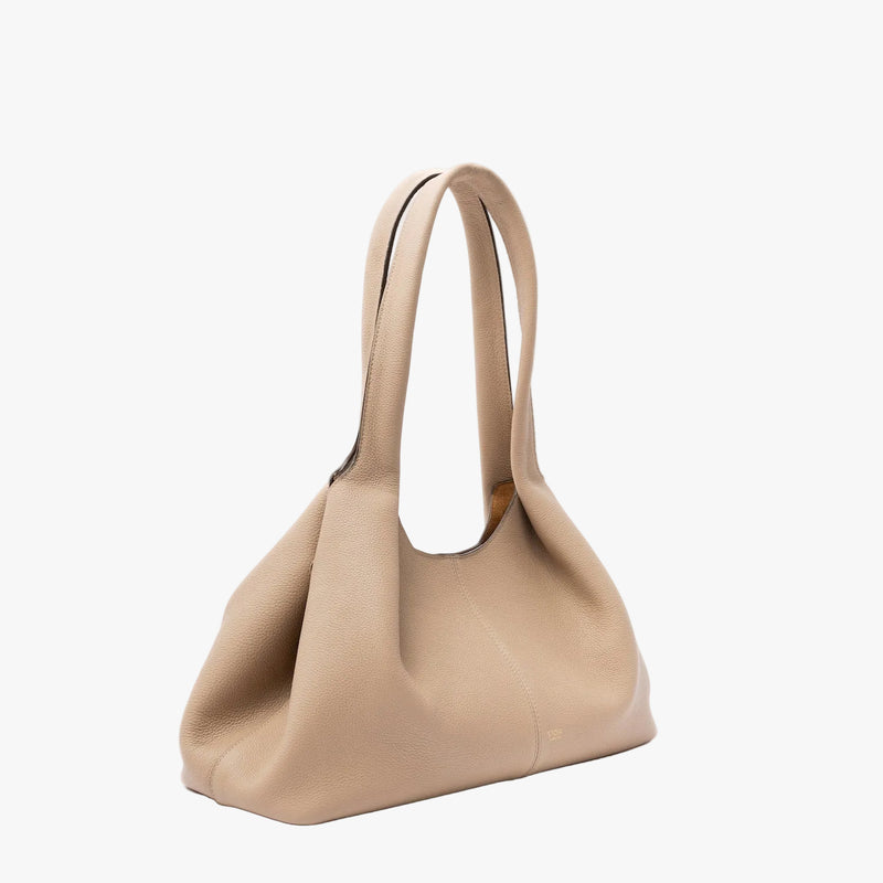 Off-axis view of STOW London's Hobo Tote in Camel pebbled leather in its triangular hobo form on a light grey background featuring a pleated front panel and small gold embossed logo