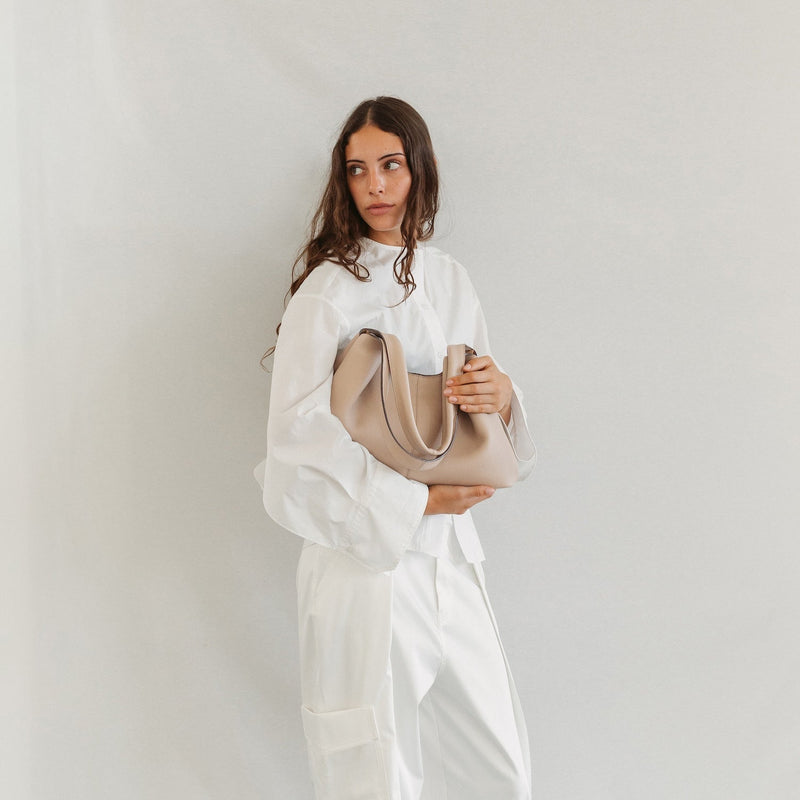 Model with STOW London's Hobo Tote in Camel pebbled leather featuring a pleated front panel and gold-coated stainless steel hardware 
