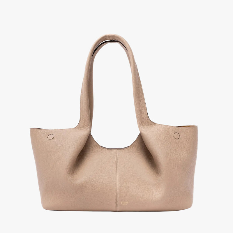 STOW London's Hobo Tote in Camel pebbled leather on a light grey background featuring a pleated front panel and small gold embossed logo