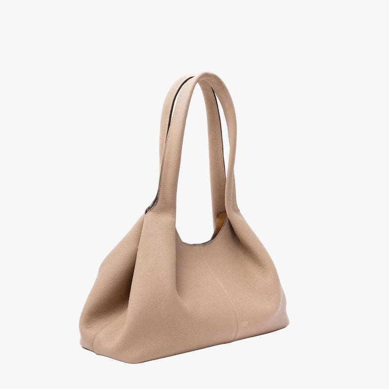 Off-axis view of STOW London's Hobo Tote in Camel pebbled leather in its triangular hobo form on a light grey background featuring a pleated front panel and small gold embossed logo