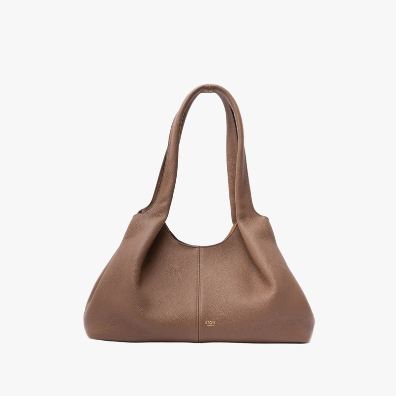 STOW London's Hobo Tote in Mocha pebbled leather in its triangular hobo shape on a light grey background featuring a pleated front panel and small gold embossed logo
