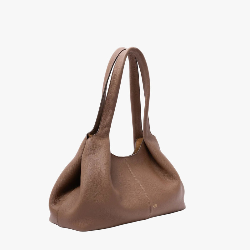 Off-axis view of STOW London's Hobo Tote in Mocha pebbled leather on a light grey background featuring a pleated front panel and small gold embossed logo
