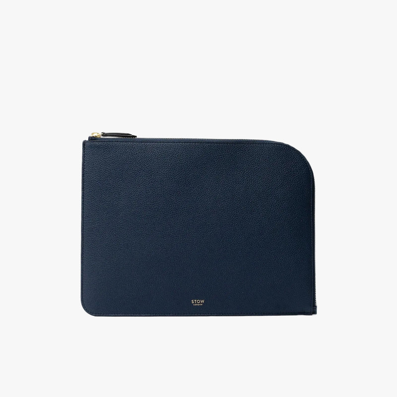 STOW London's Ipad Sleeve in Navy pebbled leather on a light grey background featuring a YKK Natulon Zip and a fine gold embossed logo on the front bottom. 