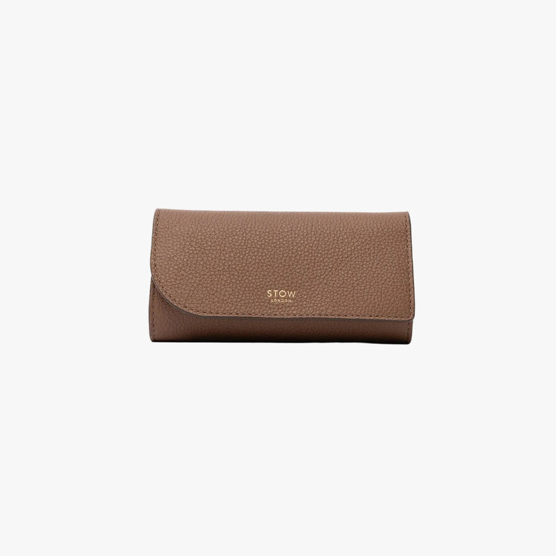 STOW London's Jewellery Roll in Mocha pebbled leather on a light grey background featuring a fine gold embossed logo on the front