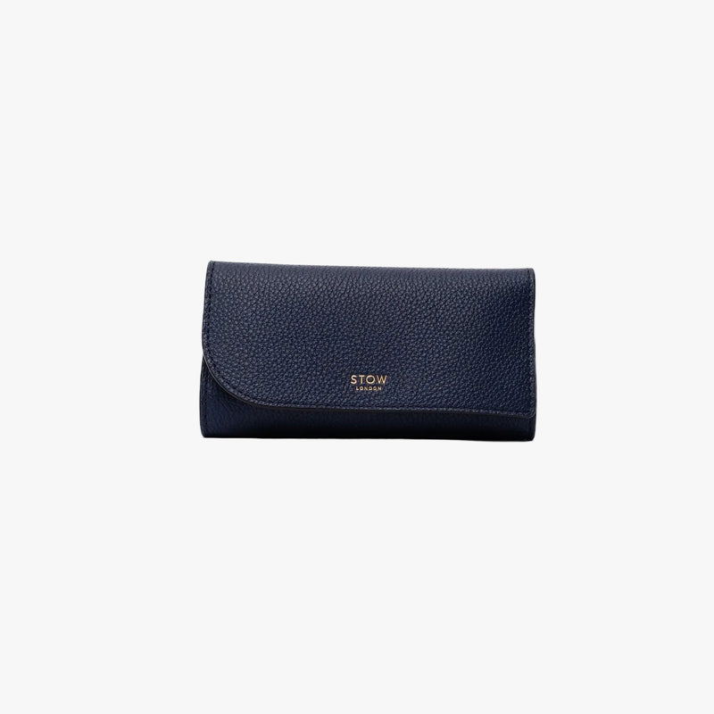 STOW London's Jewellery Roll in Navy pebbled leather on a light grey background featuring a fine gold embossed logo on the front
