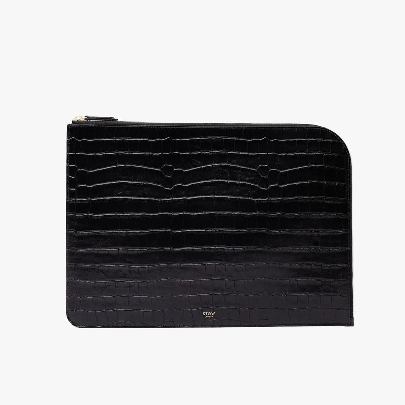 STOW London's Laptop Sleeve in Black Embossed Croc leather on a light grey background featuring a YKK Natulon Zip and a fine gold embossed logo on the front bottom. 