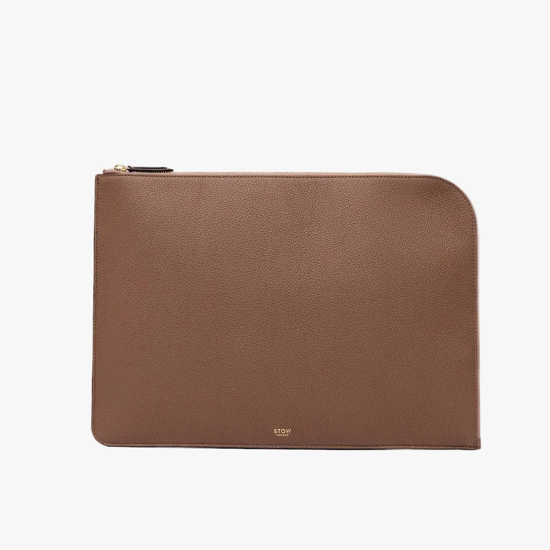 STOW London's Laptop Sleeve in Mocha pebbled leather on a light grey background featuring a YKK Natulon Zip and a fine gold embossed logo on the front bottom. 