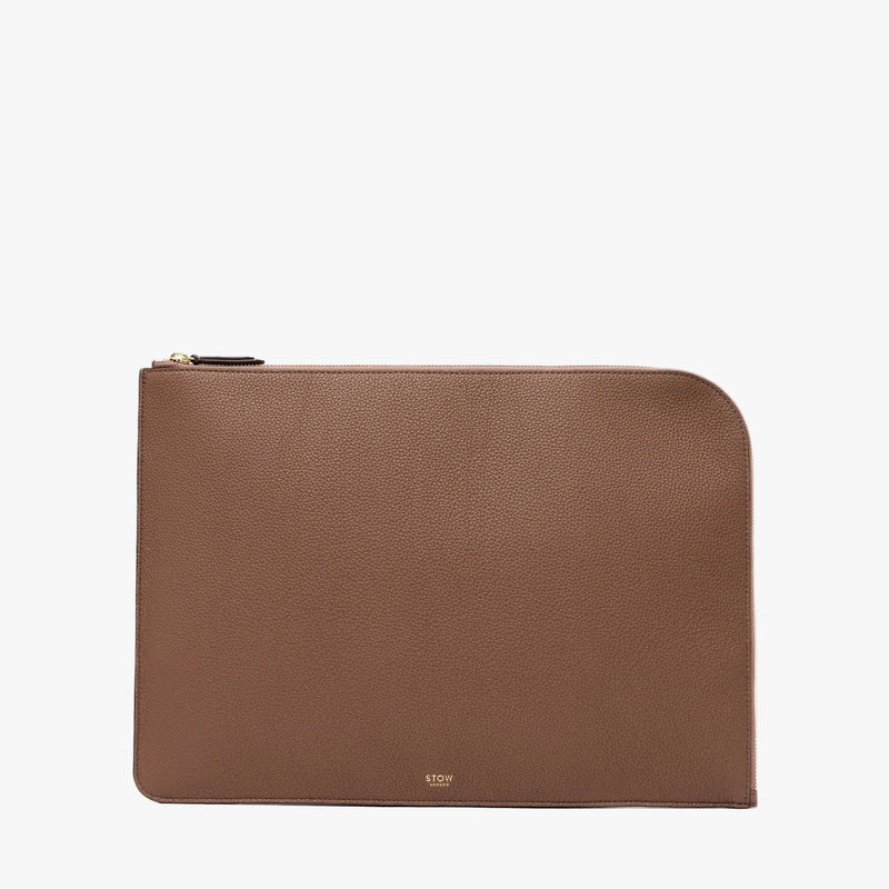 STOW London's Leather Sleeve in Mocha pebbled leather on a light grey background featuring a YKK Natulon Zip and a fine gold embossed logo on the front bottom. 