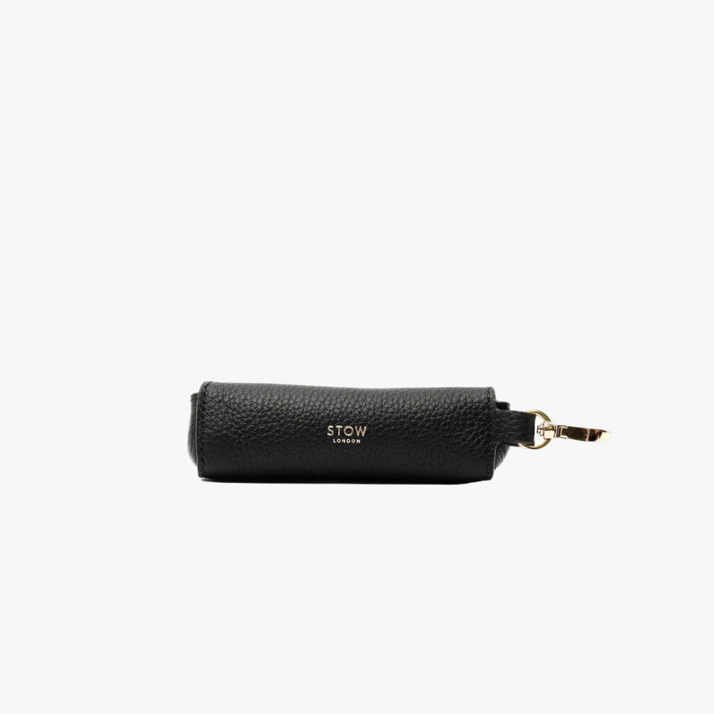 STOW London's Lipstick Case in Black pebbled leather featuring a gold-coated stainless steel clip and embossed logo on a light grey background