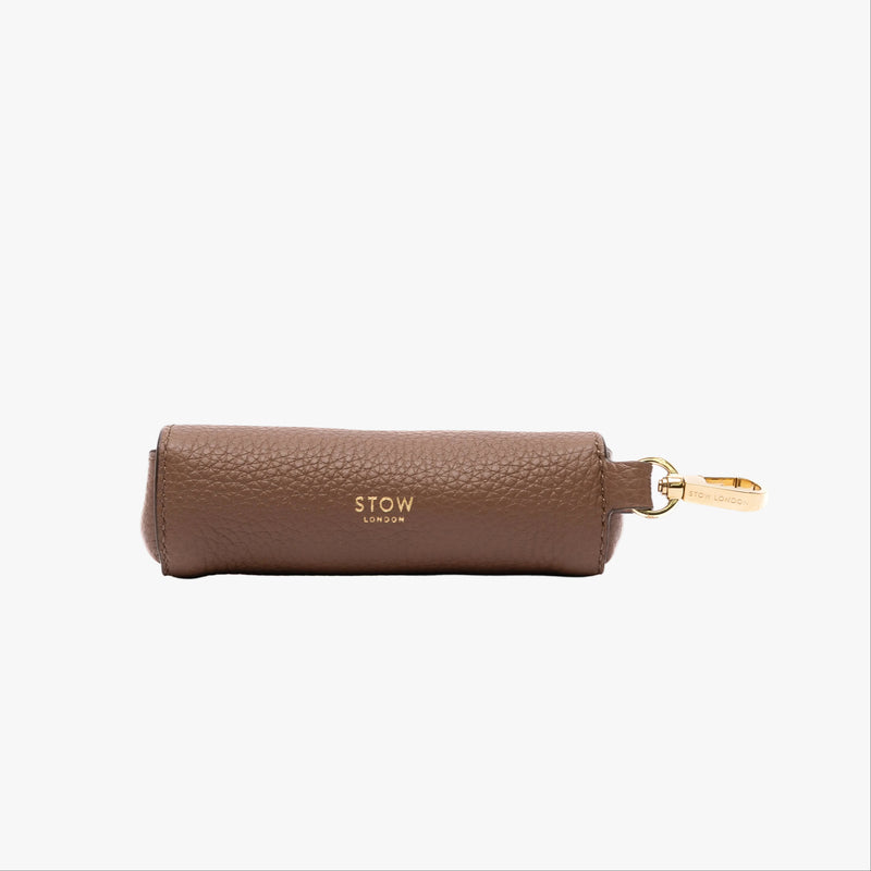 STOW London's Lipstick Case in Mocha pebbled leather on a light grey background featuring gold-coated stainless steel hardware and embossed logo