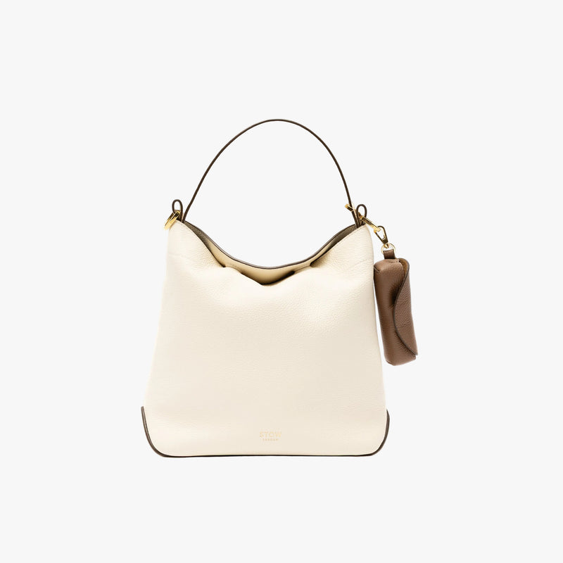 STOW London's Lipstick Case in Mocha pebbled leather on a light grey background attached to the Spring Moon Midi Curve bag by its gold-coated stainless steel clip