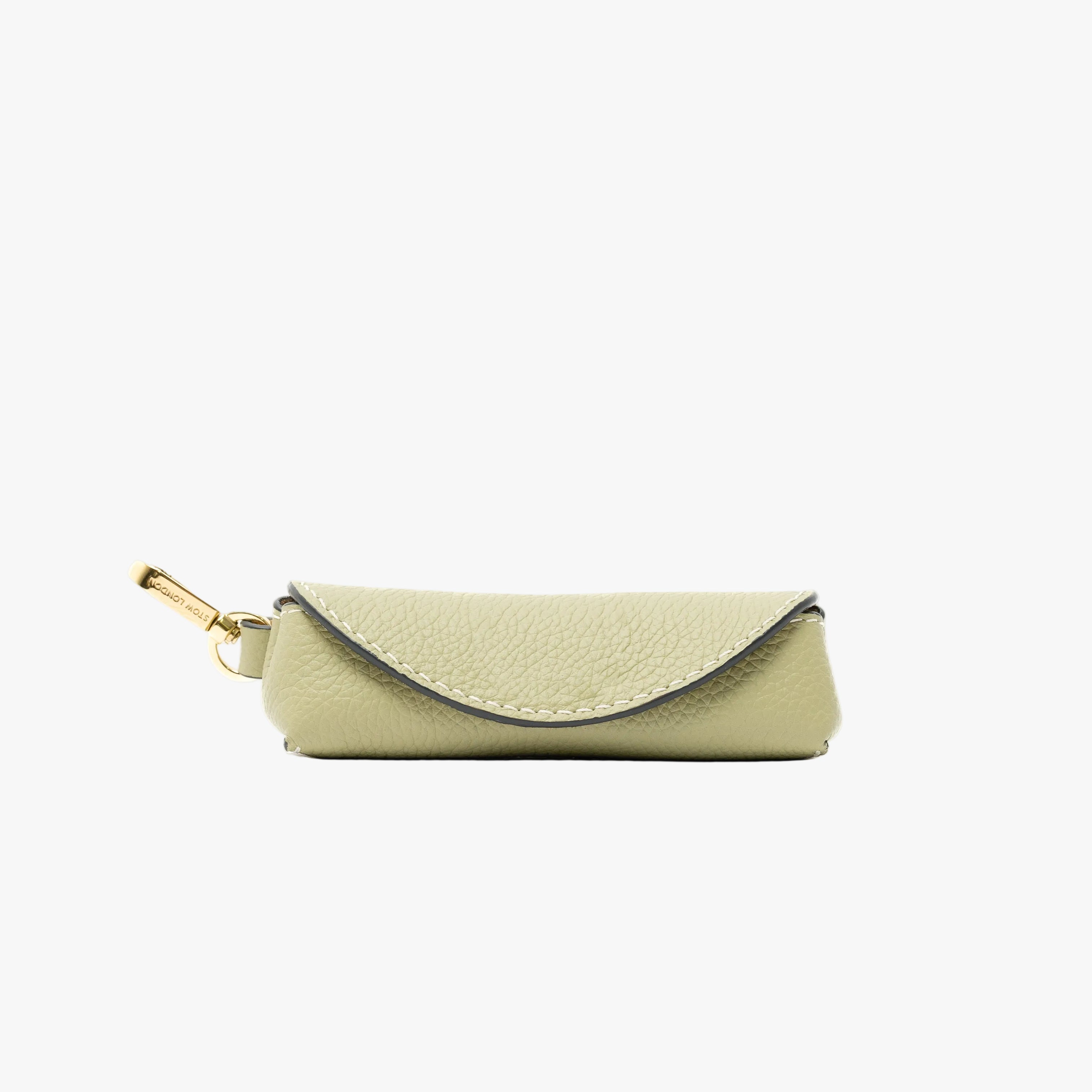 STOW London's Lipstick Case in Pale Green pebbled leather featuring a gold-coated stainless steel clip on a light grey background