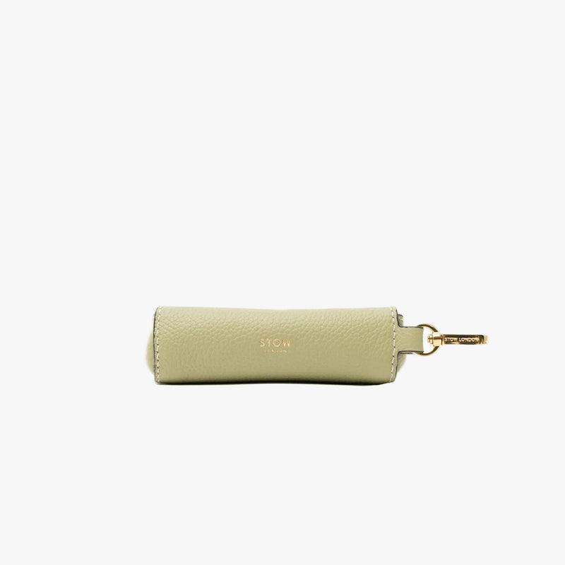 STOW London's Lipstick Case in Pale Green pebbled leather featuring a gold-coated stainless steel clip and gold embossed logo on a light grey background