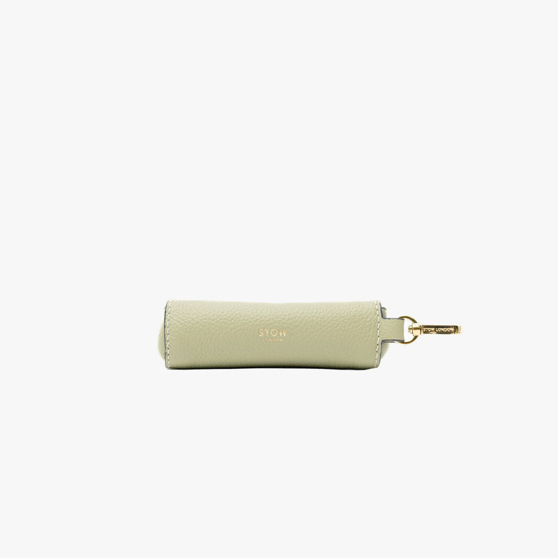 Back panel of STOW London's Lipstick Case in Pale Green pebbled leather featuring a gold-coated stainless steel clip and small embossed logo on a light grey background
