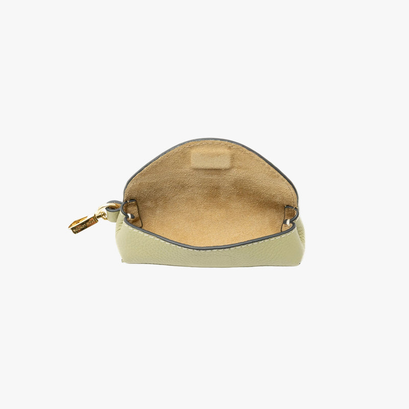 STOW London's Lipstick Case in Pale Green pebbled leather with flap open showing hidden magnetic closure and suede interior lining featuring a gold-coated stainless steel clip on a light grey background