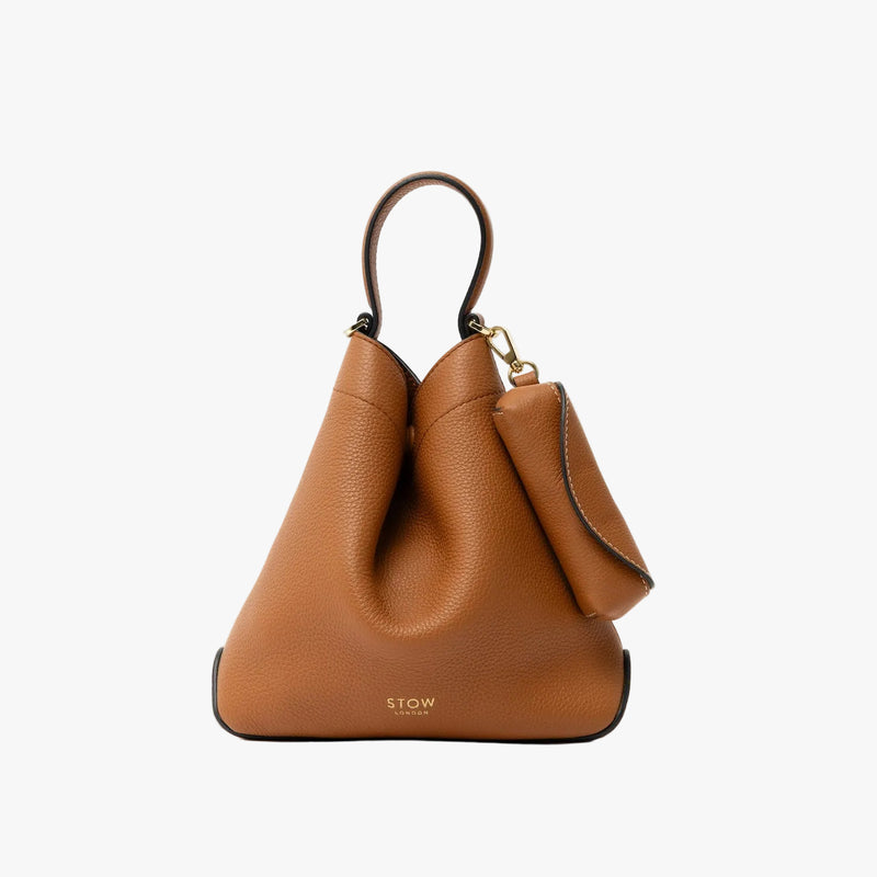 STOW London's Lipstick Case in Earth Tan pebbled leather attached by a gold-coated stainless steel clip to the matching Mini Curve Bag on a light grey background