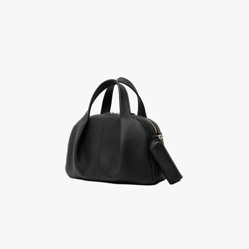 STOW London's Lipstick Case in Black pebbled leather attached by a gold-coated stainless steel clip to the matching Mini Bowling bag on a light grey background