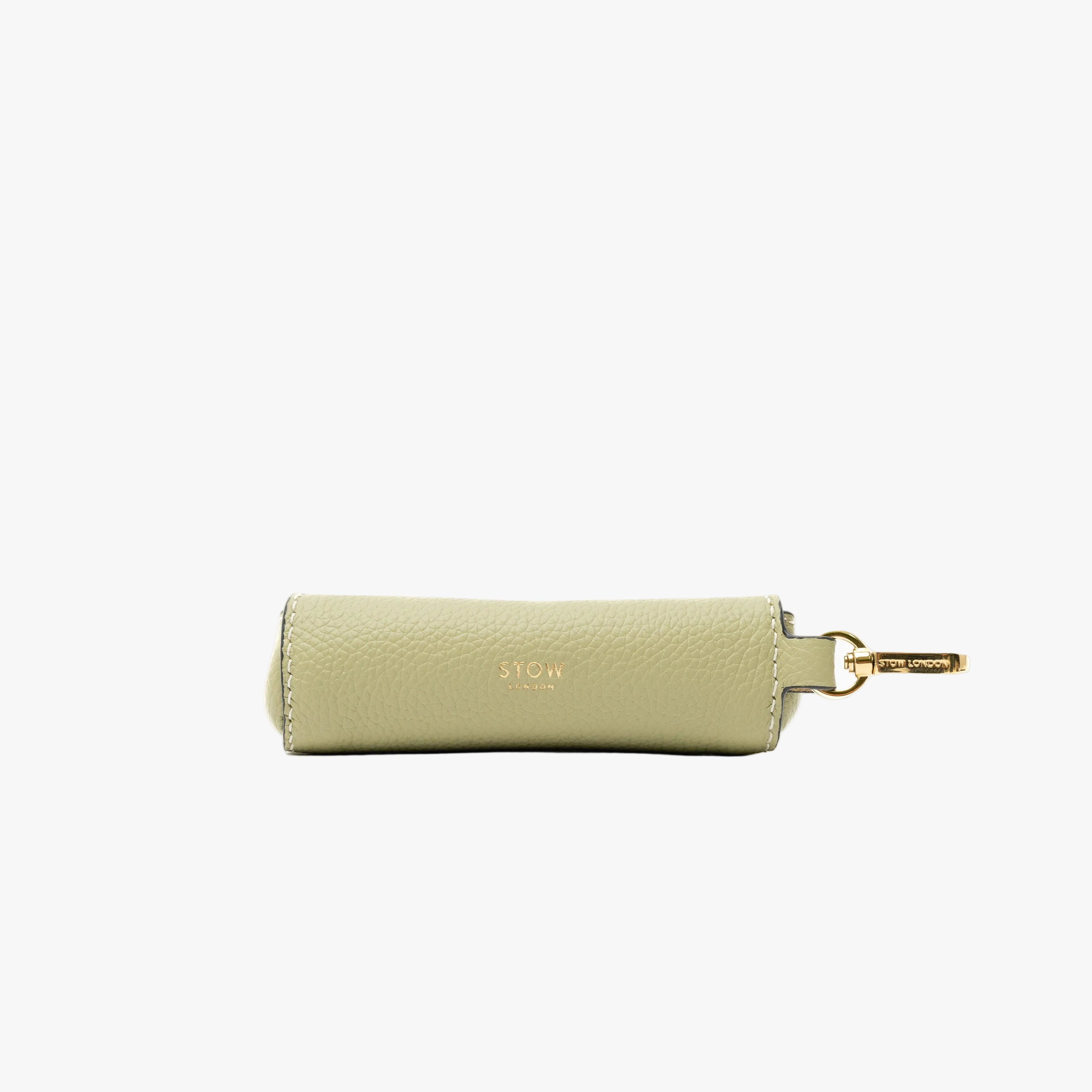STOW London's Lipstick Case in Pale Green pebbled leather featuring a gold-coated stainless steel clip and gold embossed logo on a light grey background