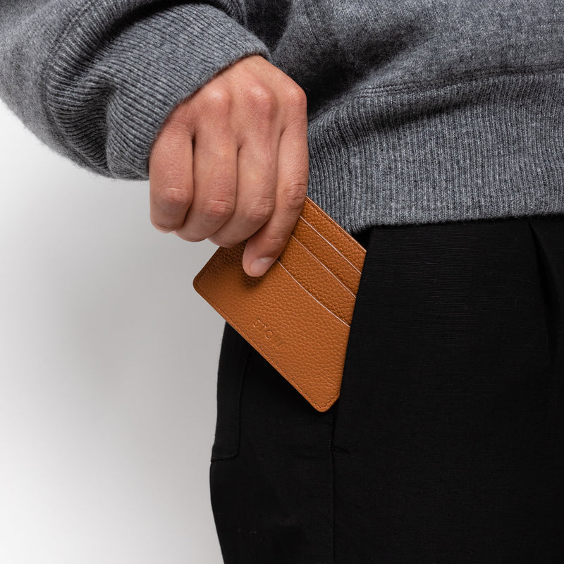 STOW London Leather Cardholder in Earth Tan colour. Male model placing cardholder into pocket