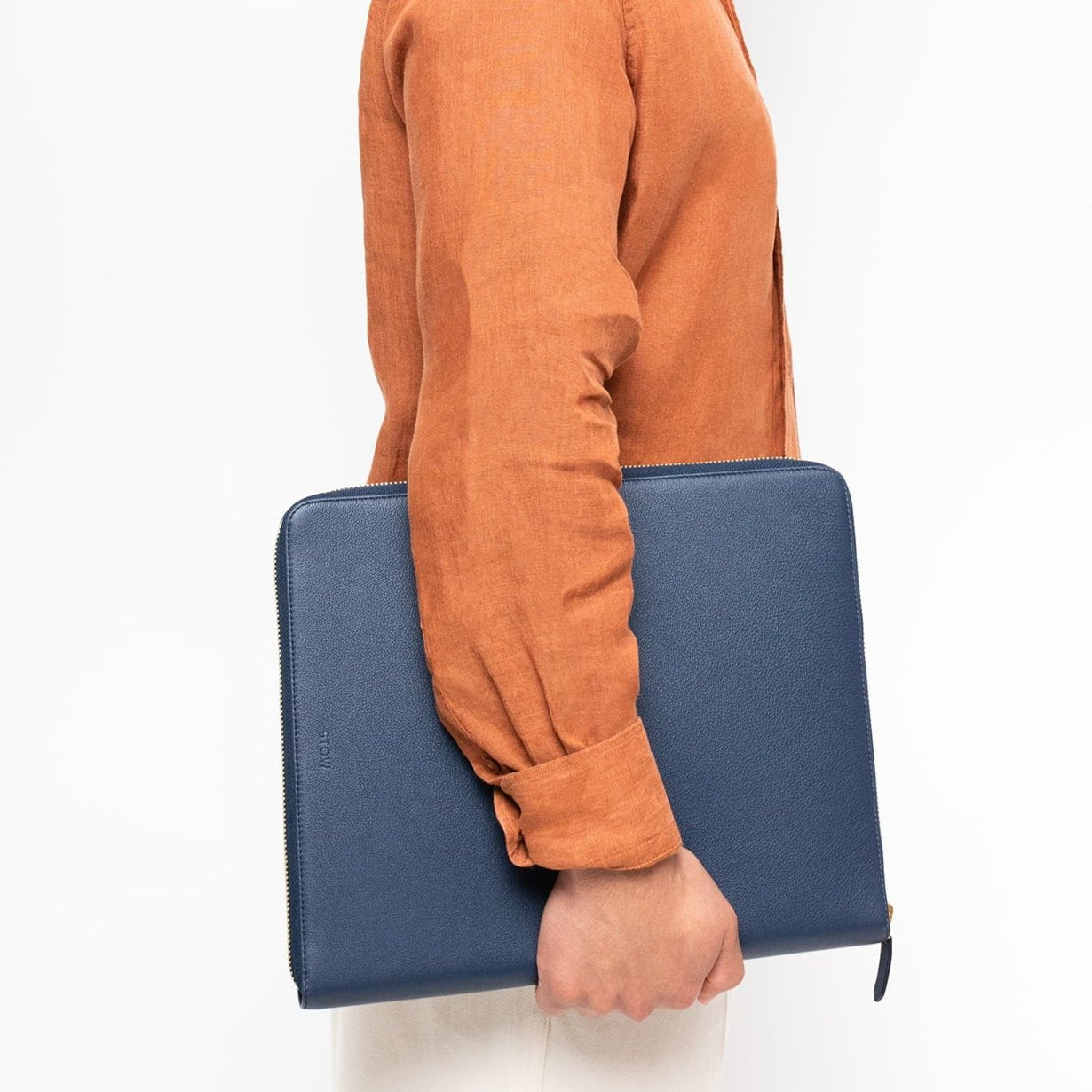 STOW London Executive Folio tech case in Navy leather held by male model wearing rust coloured shirt