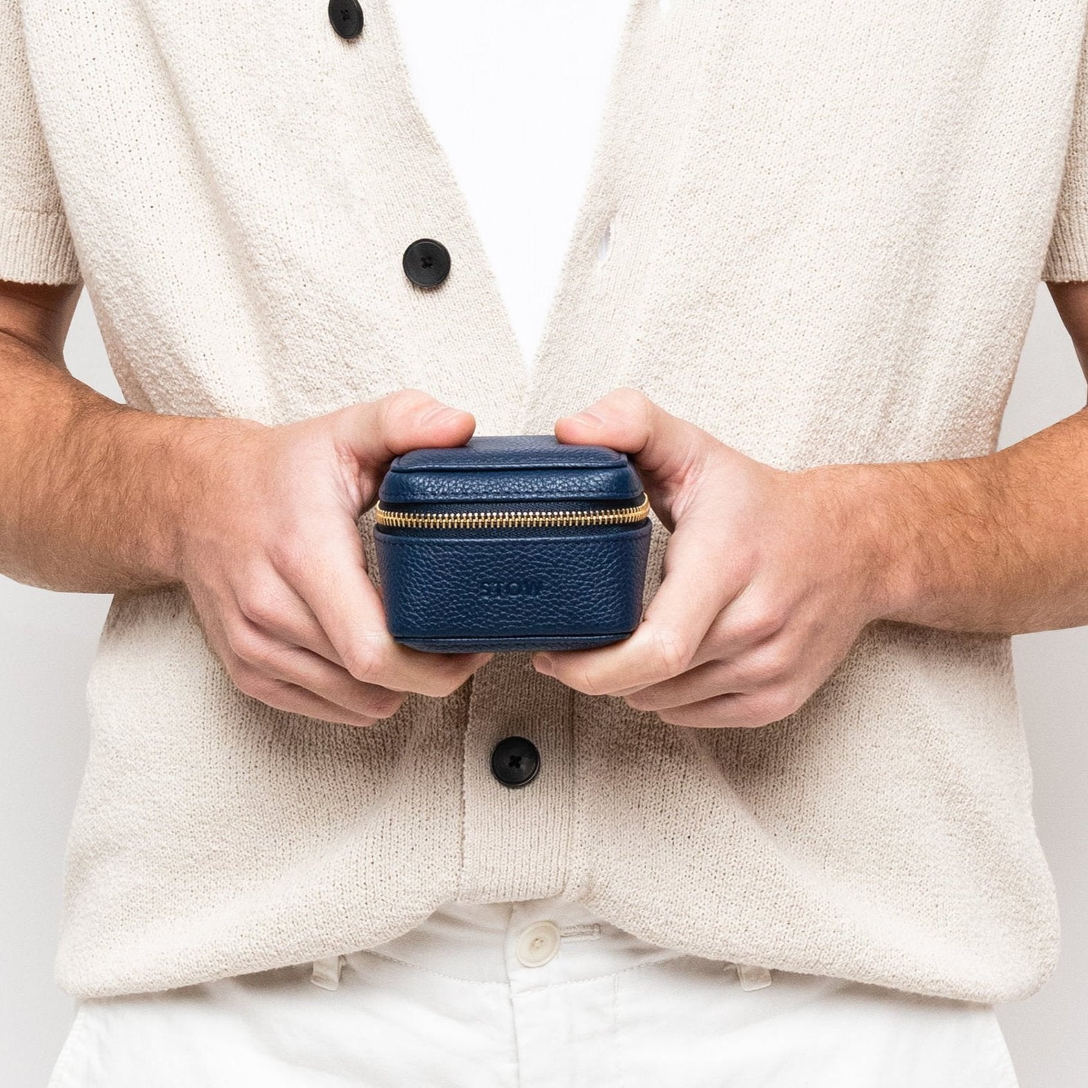 STOW London Hester Essentials Case in Navy leather being held in hands