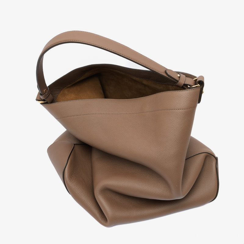 STOW London's Maxi Curve bag in Mocha pebbled leather featuring gold-coated stainless steel hardware on a light grey background