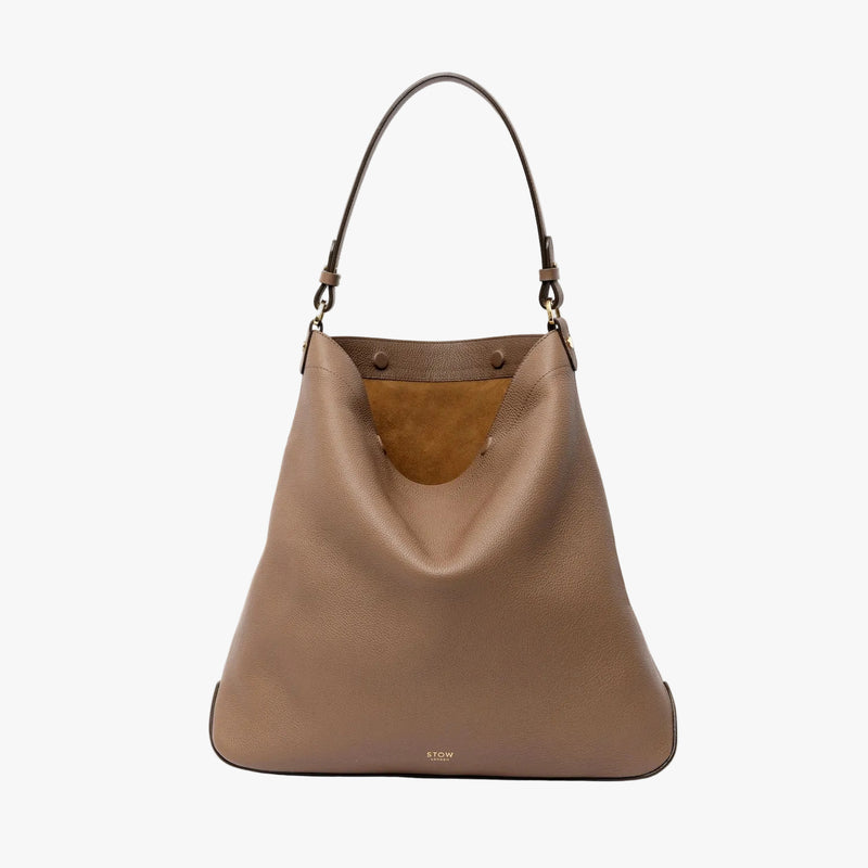 STOW London's Maxi Curve bag in Mocha pebbled leather featuring gold-coated stainless steel hardware on a light grey background