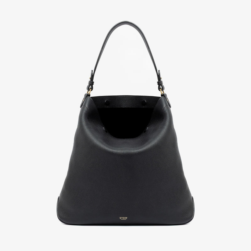 STOW London's Maxi Curve bag in Black pebbled leather with magnets open showing the black suede interior lining featuring gold-coated stainless steel hardware on a light grey background
