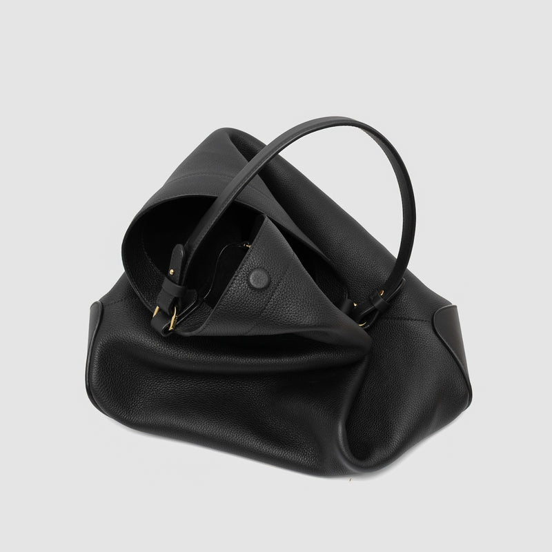 STOW London's Maxi Curve bag in Black pebbled leather featuring gold-coated stainless steel hardware on a light grey background