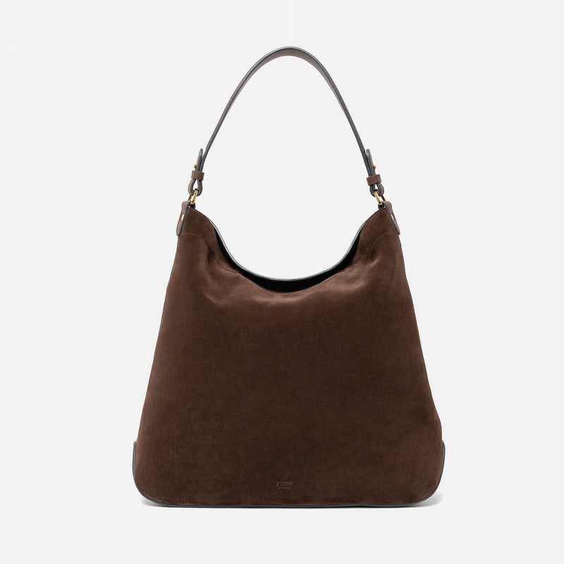 STOW London's Maxi Curve bag in Chocolate suede leather featuring gold-coated stainless steel hardware on a light grey background