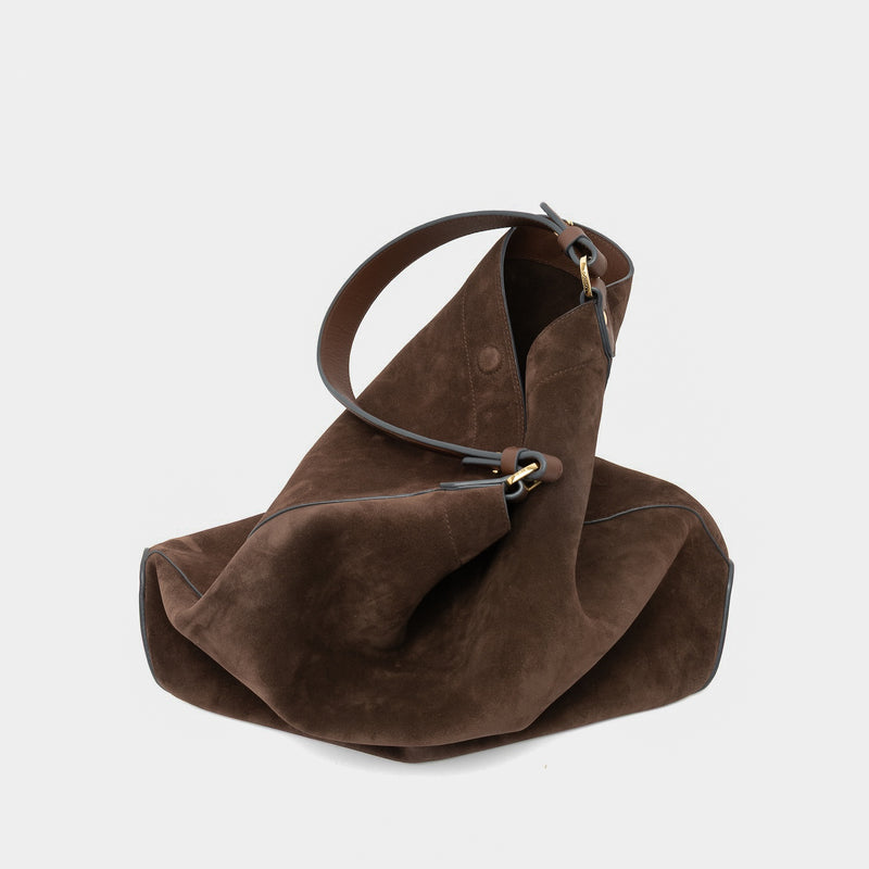 STOW London's Maxi Curve bag in Chocolate suede leather featuring gold-coated stainless steel hardware on a light grey background