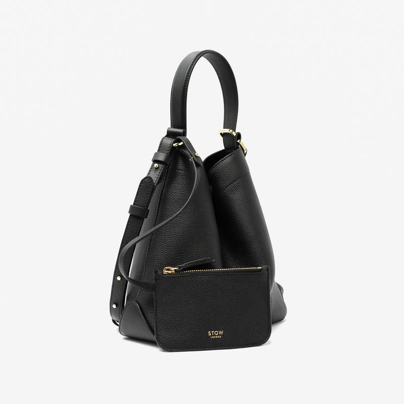 STOW London's Midi Curve in Black pebbled leather with its matching, detachable interior pouch featuring gold-coated stainless steel hardware on a light grey background