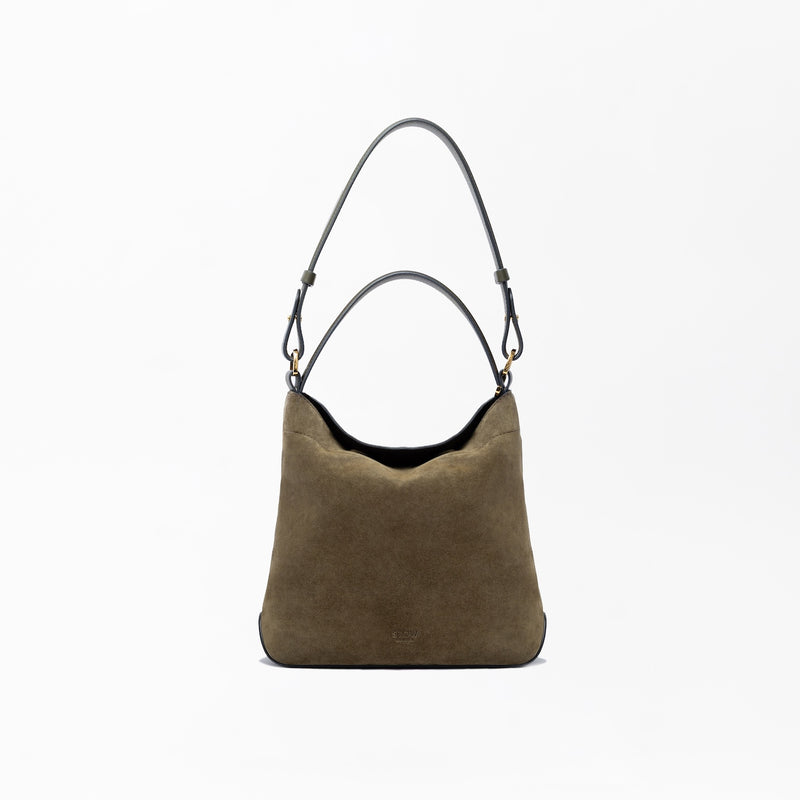 STOW London's Midi Curve in Dark Green suede leather on a light grey background featuring the detachable shoulder strap and top handle with gold hardware and details 