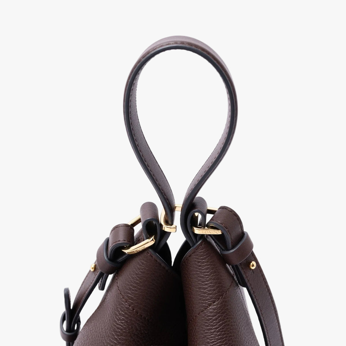 Close up of the top handle and gold-coated stainless steel hardware on STOW London's Midi Curve in Espresso pebbled leather on a light grey background