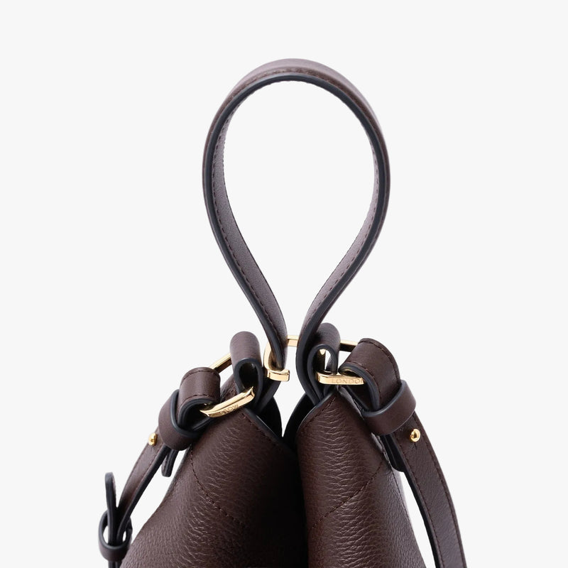 Close up of the top handle and gold-coated stainless steel hardware on STOW London's Midi Curve in Espresso pebbled leather on a light grey background