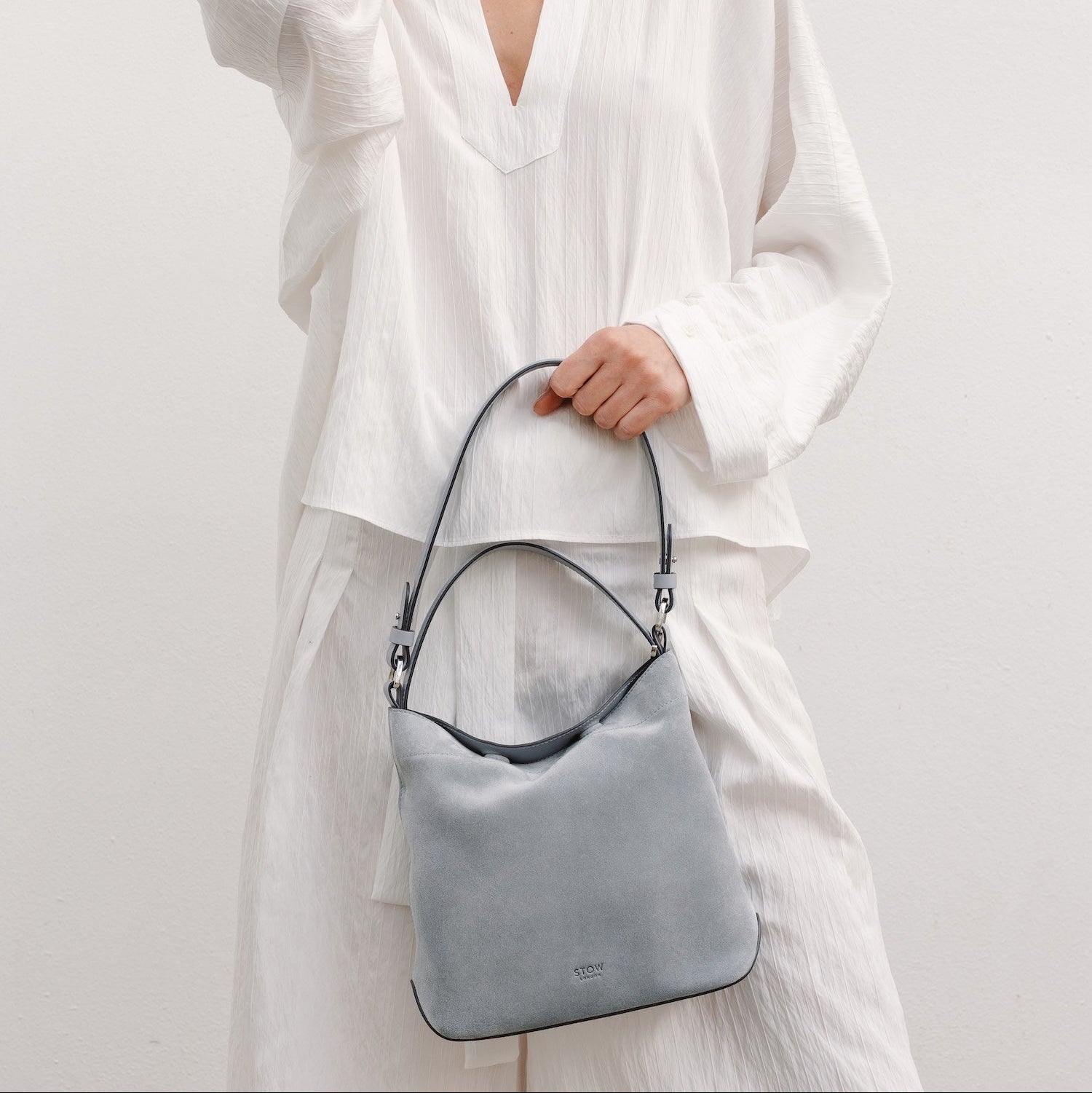 Model with STOW London's Midi Curve in Misty Blue suede featuring the detachable shoulder strap