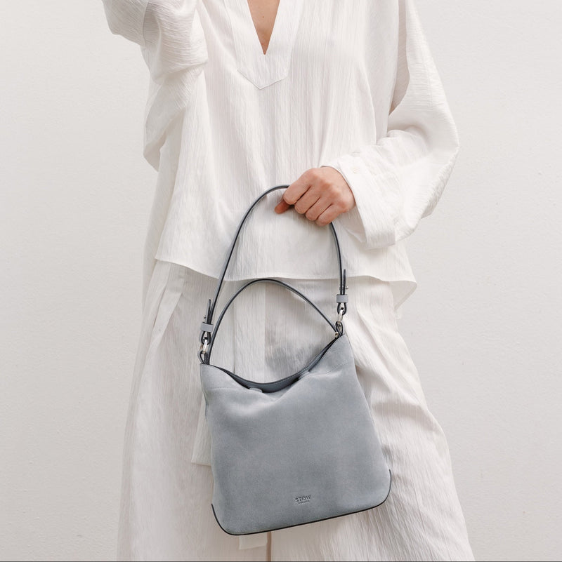 Model with STOW London's Midi Curve in Misty Blue suede featuring the detachable shoulder strap