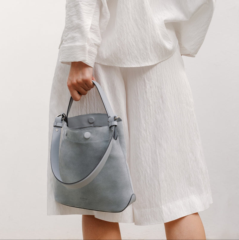 Model with STOW London's Midi Curve in Misty Blue suede featuring the detachable shoulder strap