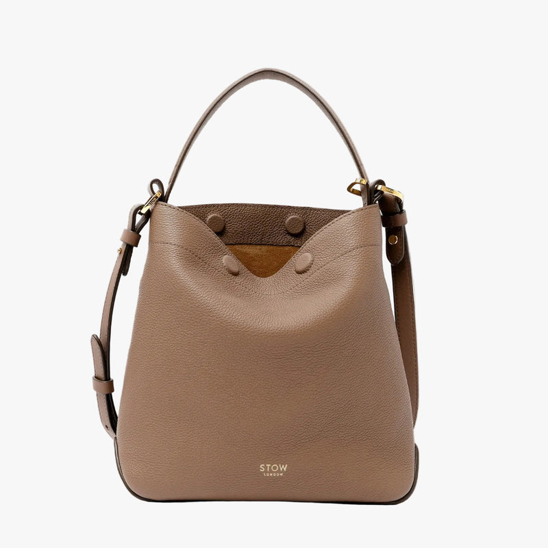 STOW London's Midi Curve bag in Mocha pebbled leather featuring gold-coated stainless steel hardware on a light grey background
